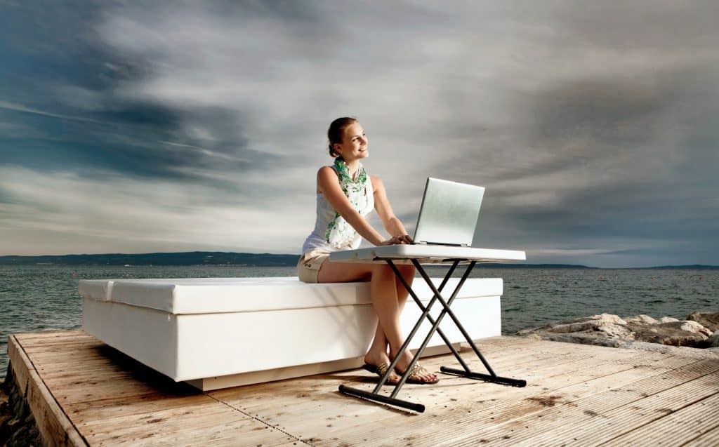 A picture of a lady with a laptop at seaside.