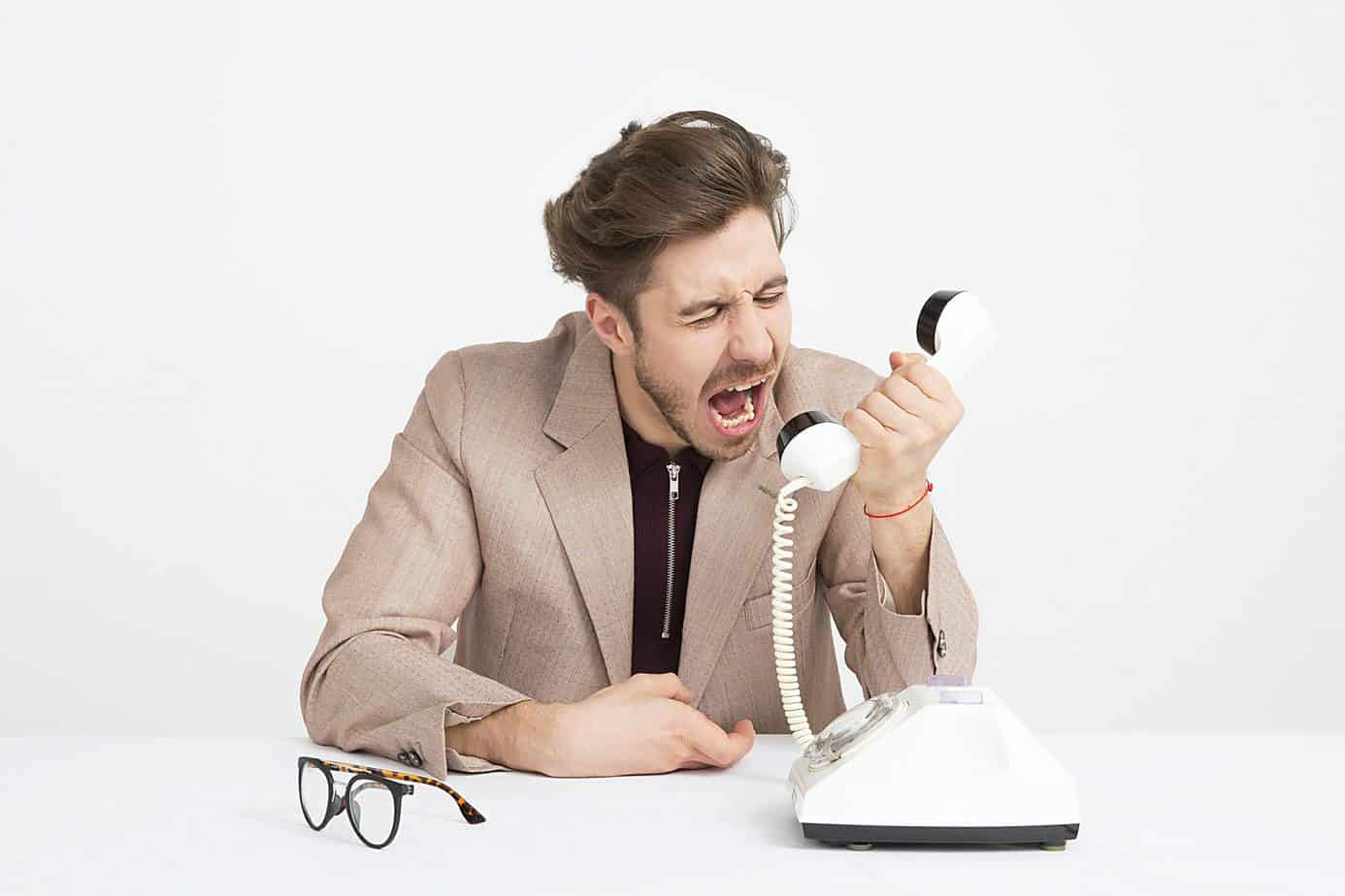 A picture of a person losing his cool while holding a telephone.