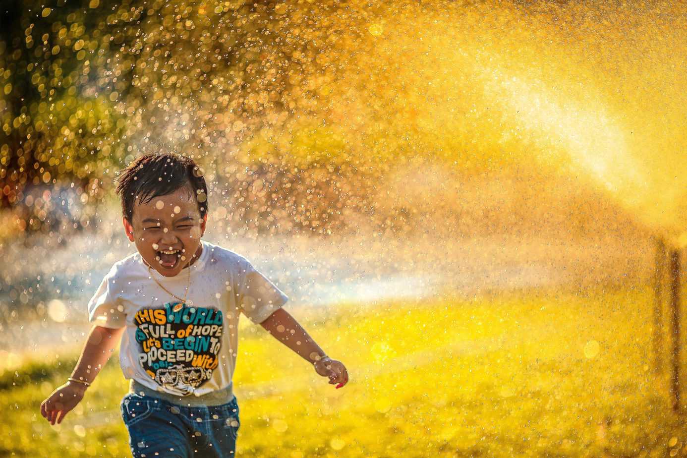 A picture of a kid running happily in the rain.