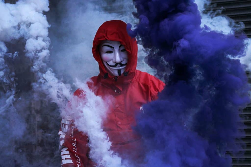 A person in a red jumpsuit wearing an anonymous mask that is synonymous with our ego.