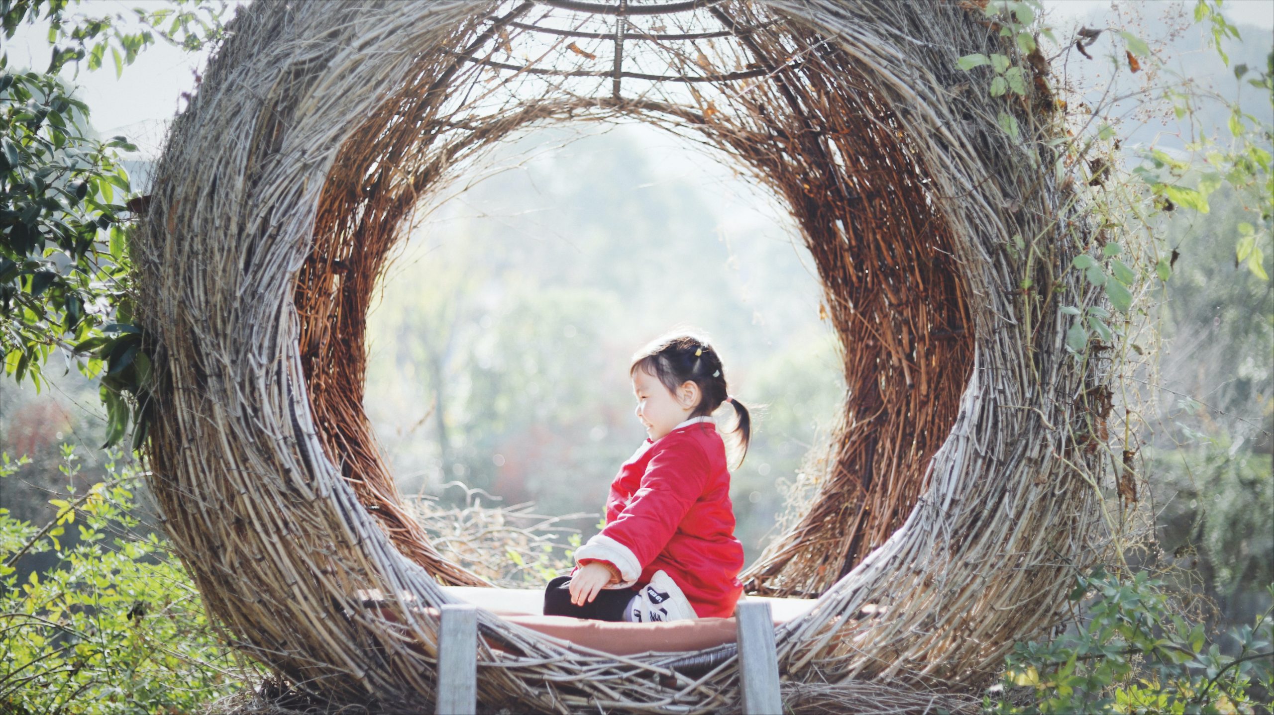 A child wearing a red dress sitting on a swing.